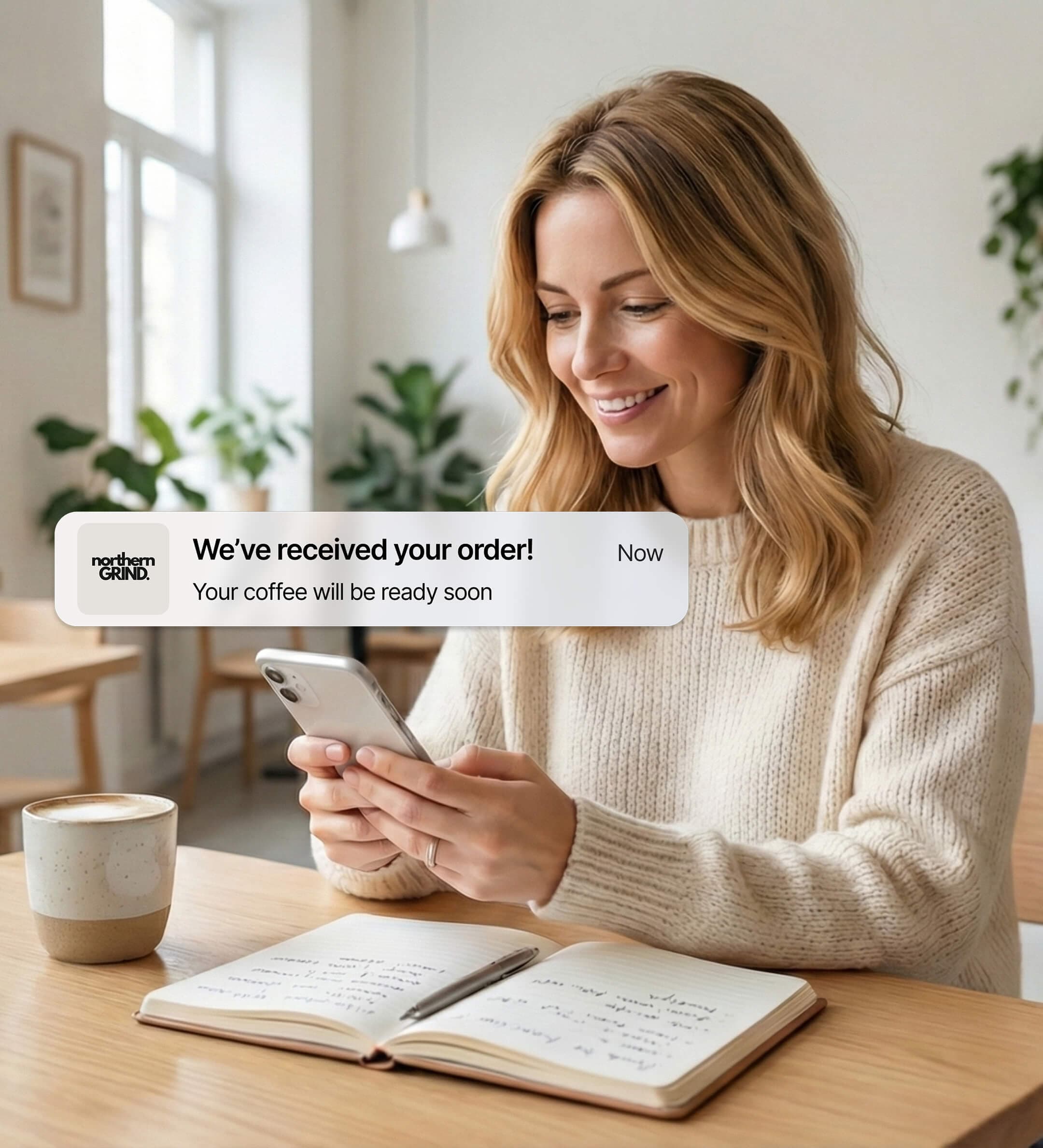 A woman is sitting in a cafe and using Sizzle to order herself a coffee